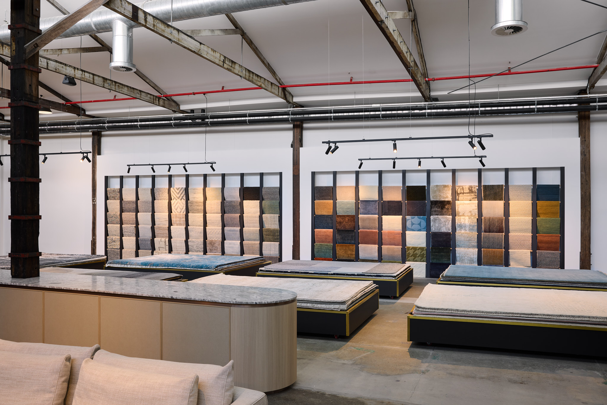 Luma Developments An industrial-style showroom featuring wall-mounted tile displays and expansive sample tables.